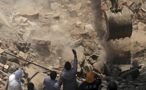 A crane clears debris of a building that collapsed to look for survivors in Mumbai, India, Friday, March 14, 2014. A seven-story residential building collapsed Friday in a Mumbai suburb and up to 10 people may be trapped under the debris, Indian officials said. (AP Photo/Rafiq Maqbool)
