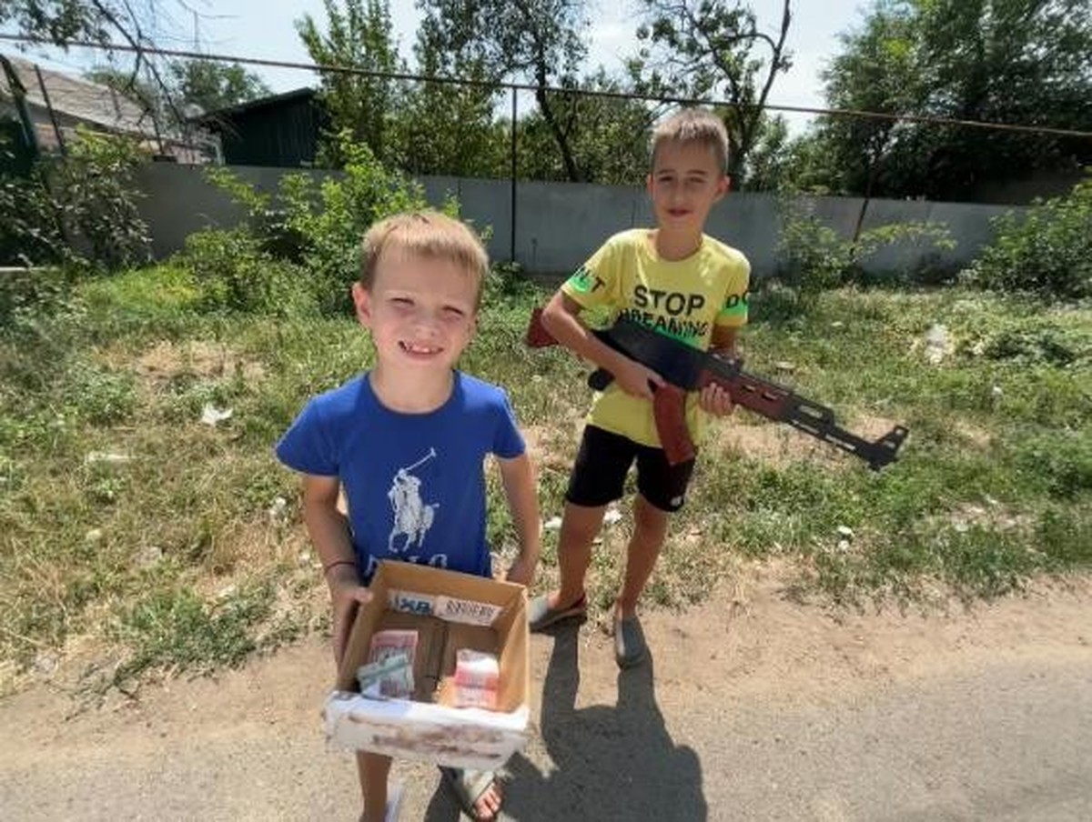 Ukrainische Buben, die Krieg spielen und an einer simulierten Strassensperre Geld sammeln.