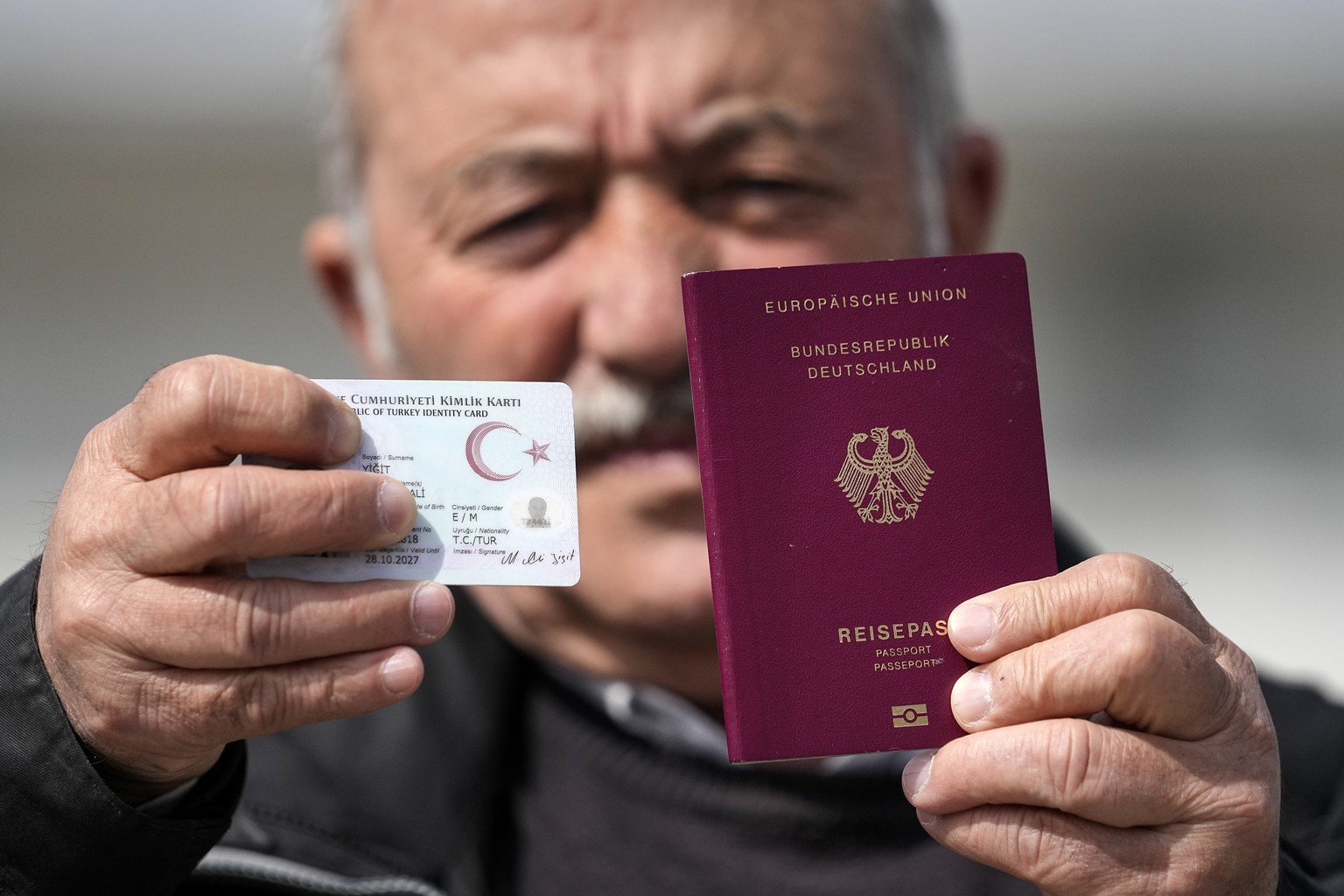 Mehmet Ali Yigit, who has been living in Germany for more than 50 years, shows his German passport and Turkish ID after he voted at the Gruga Hall in Essen, Germany, Thursday, April 27, 2023. Millions ...