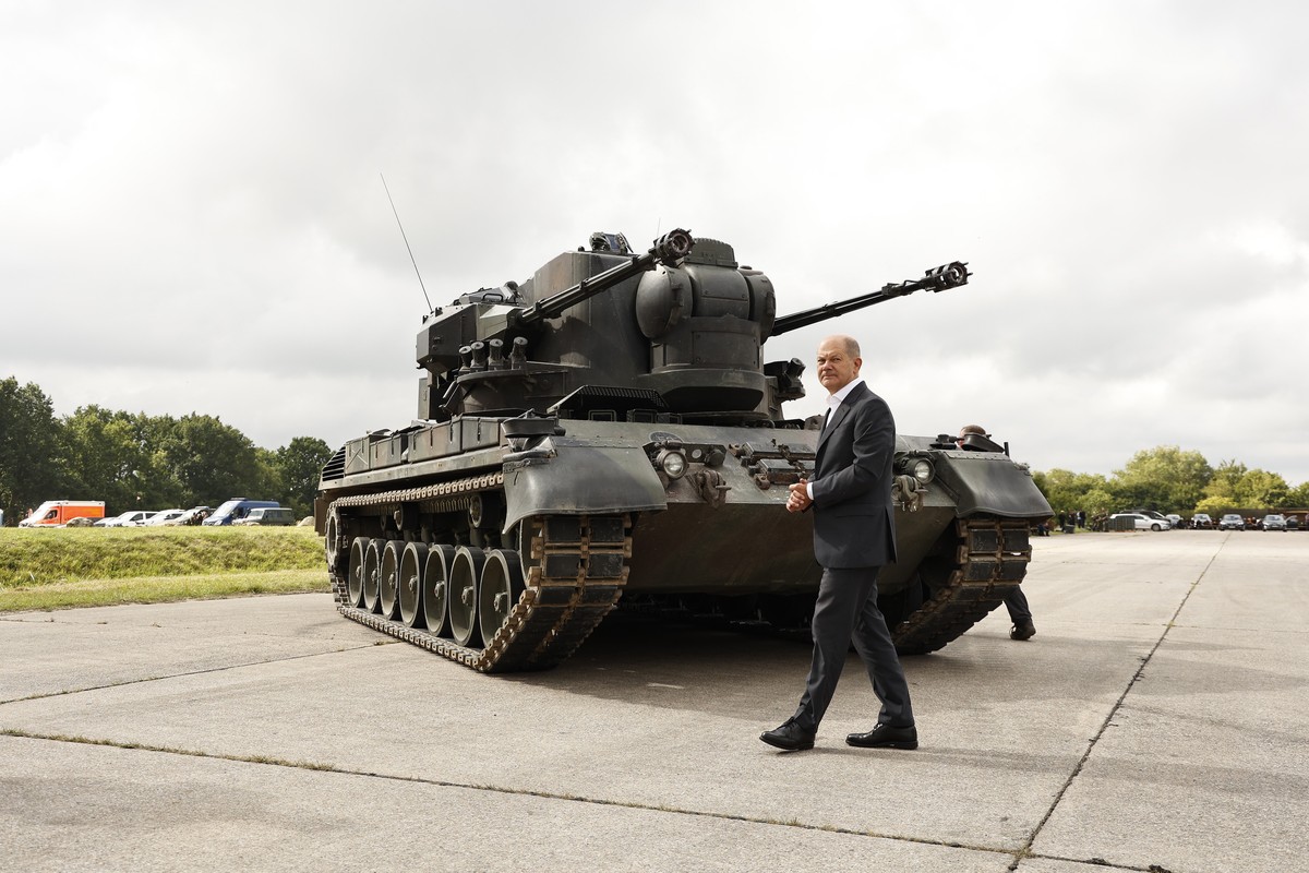 epa10137718 German Chancellor Olaf Scholz poses in front of an anti-aircraft gun tank Gepard during his visit a training facility of the arms-maker Krauss-Maffei Wegmann at the Putlos military trainin ...