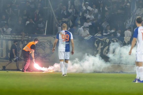 A security member removes a light smoke flare launched by Grasshoppers ultras onto the pitch after Lausannes players scored the 2:0, during the Swiss Cup semifinal between FC Stade Lausanne-Ouchy, S ...