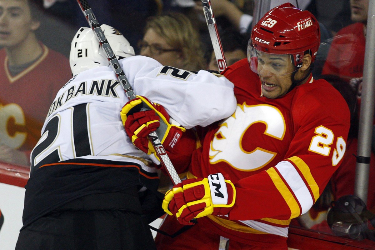 FILE - In this April 7, 2012, file photo, Anaheim Ducks' Sheldon Brookbank, left, checks Calgary Flames' Akim Aliu, a Nigerian-born Canadian, during third period NHL hockey action in Calgary ...