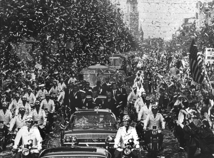 US President John Fitzgerald Kennedy (left) is celebrated with a confetti rain as he is escorted in an open limousine through the Rheinstrasse in West Berlin, June 26, 1963. The president is accompani ...