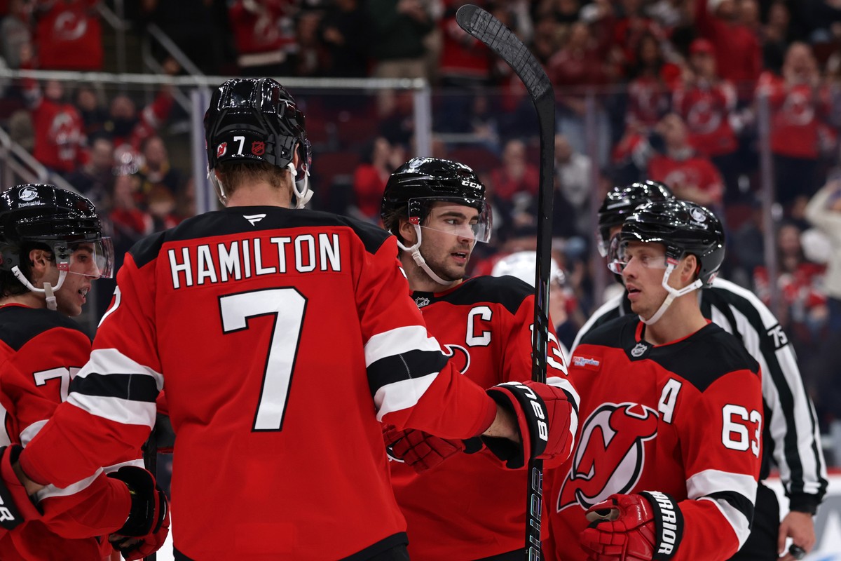 New Jersey Devils center Nico Hischier (13) is congratulated by Jesper Bratt (63) and Dougie Hamilton (7) after scoring a goal during the second period of an NHL hockey game against the Vancouver Canu ...
