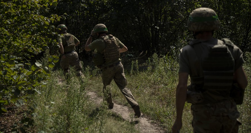 Ukrainian soldiers run towards a mortar position on the front line in the outskirts of Kreminna, Ukraine, Wednesday, August 16, 2023. (AP Photo/Bram Janssen)