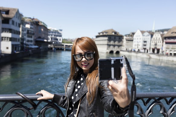 ZUM THEMA SOMMERTOURISTEN IN DER SCHWEIZ STELLEN WIR IHNEN HEUTE, DONNERSTAG, 28.07.2016, FOLGENDES NEUES BILDMATERIAL ZUR VERFUEGUNG --- A female Asian tourist takes a selfie standing on the Muenster ...