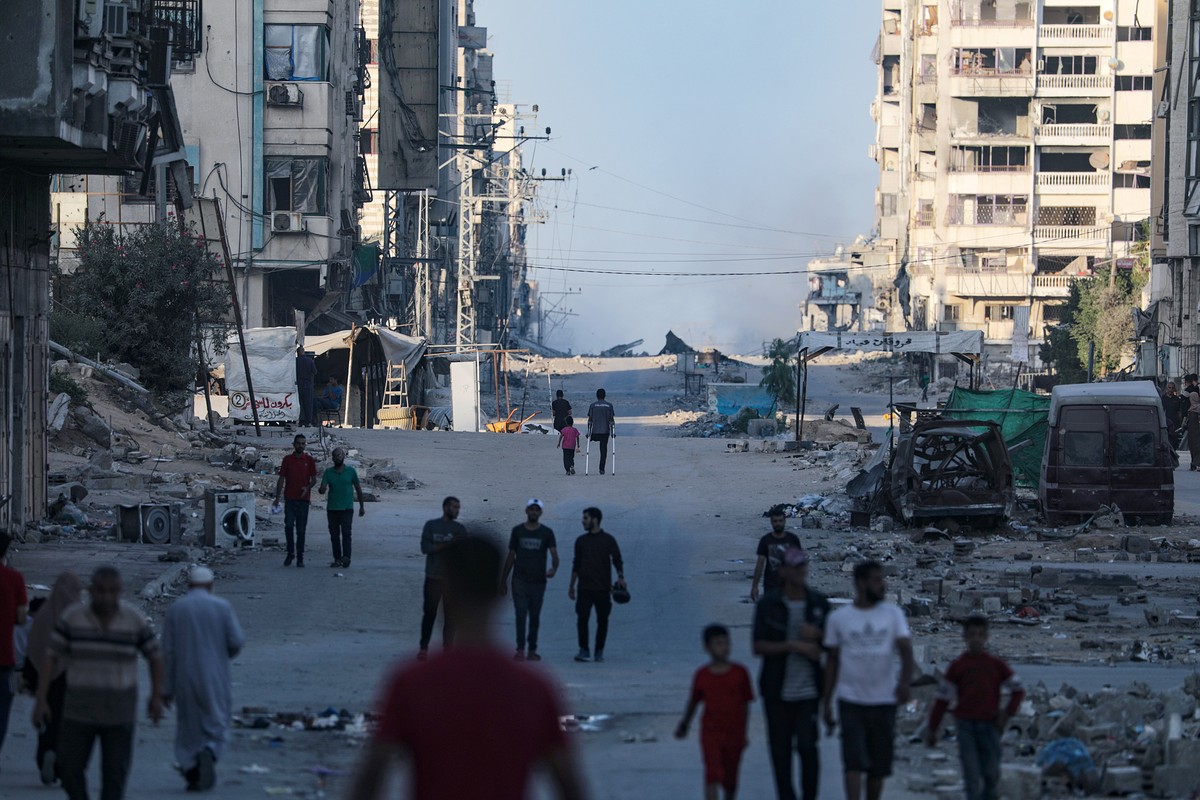 epa12435127 Palestinians move at Al Jalaa street as smoke rises following Israeli air strike during an Israeli military operation in Gaza City, Gaza Strip, 06 October 2025. According to the UN around  ...