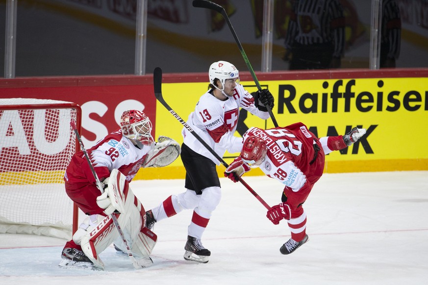 Switzerland&#039;s forward Nico Hischier, centre, checks Denmark&#039;s defender Emil Kristensen, right, past goaltender Sebastian Dahm, left, during the IIHF 2021 World Championship preliminary round ...