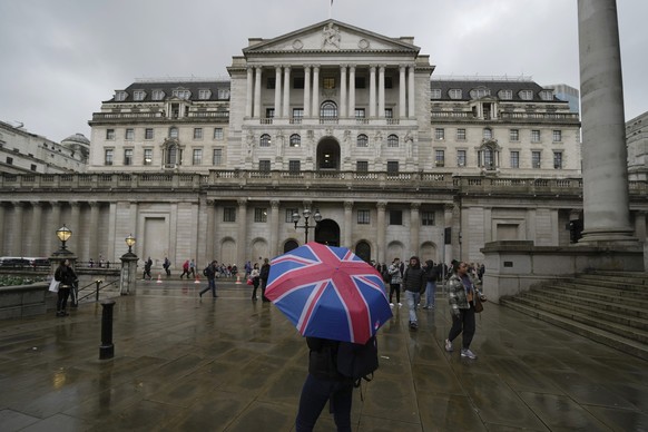 FILE - A woman with an umbrella stands in front of the Bank of England, at the financial district in London, Thursday, Nov. 3, 2022. From winemakers in California to startups across the Atlantic Ocean ...