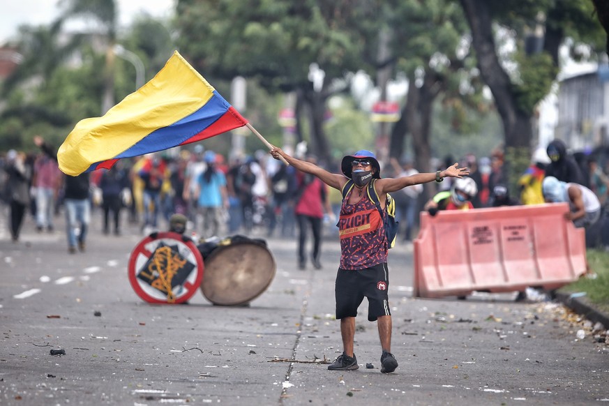 epa09355751 A protester waves a Colombian flag during clashes with members of the Mobile Anti-Riot Squad (ESMAD) of the Colombian Police at the Loma de la Cruz sector in Cali, Colombia, 20 July 2021.  ...