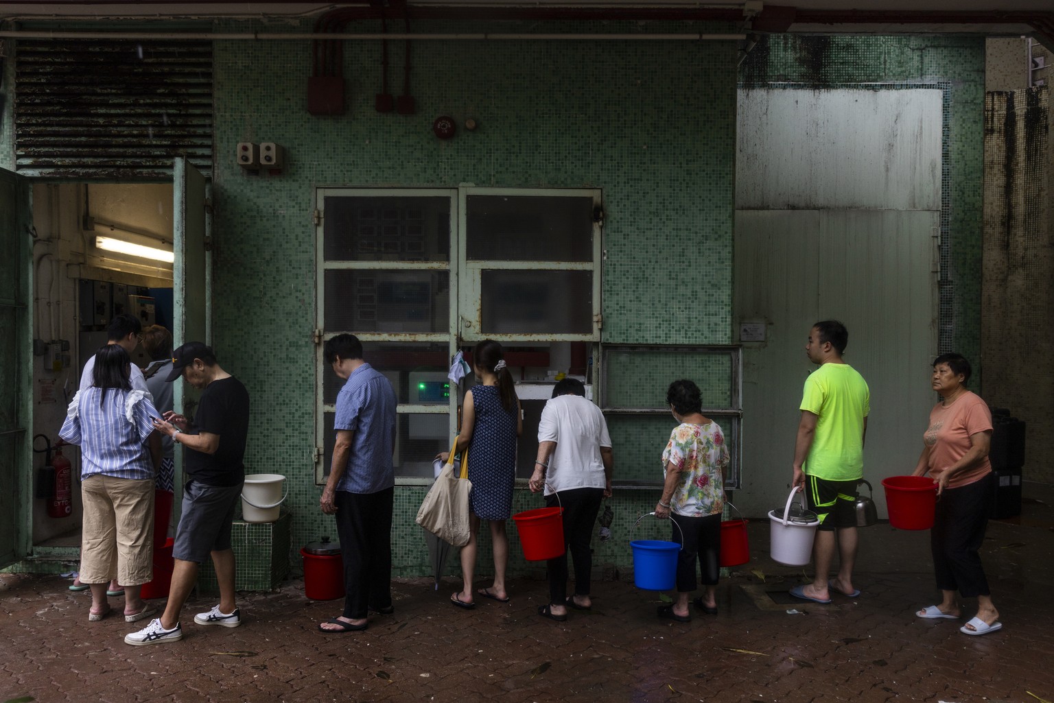 Residents line up to collect water after a pipe burst following landslide and heavy rainstorms in Hong Kong, Friday, Sept. 8, 2023. (AP Photo/Louise Delmotte)