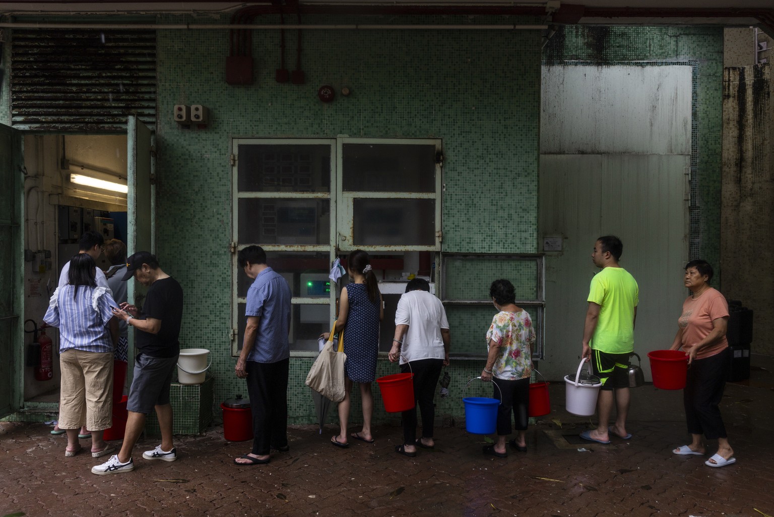 Residents queue to get water after a pipe burst following landslides and heavy rain in Hong Kong Friday, Sept. 8, 2023. (AP Photo/Louise Delmotte)