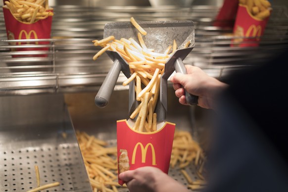 ZUM FASTFOOD-RESTAURANT MCDONALD&#039;S STELLEN WIR IHNEN HEUTE, MITTWOCH, 8. MAERZ 2017, FOLGENDES BILDMATERIAL ZUR VERFUEGUNG --- An employee fills French fries into a box in the kitchen of a McDona ...