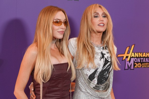 Alex Cooper, left, and Miley Cyrus arrive at the premiere of "Hannah Montana 20th Anniversary Special" on Monday, March 23, 2026, at El Capitan Theatre in Los Angeles. (AP Photo/Chris Pizzel ...