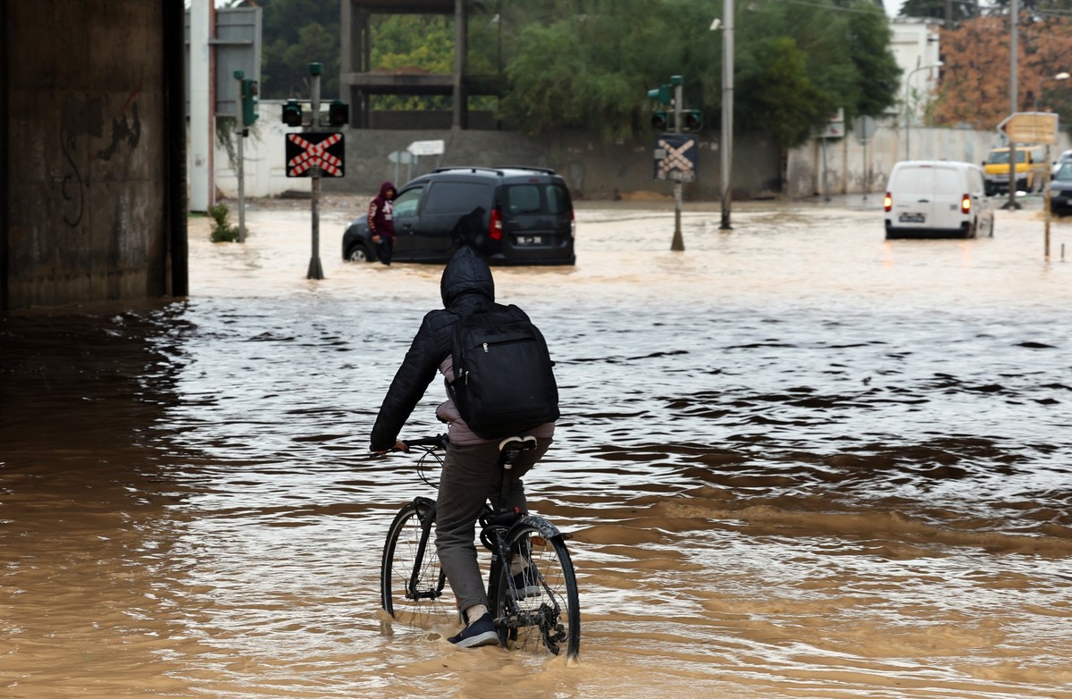 epa12664679 A person rides a bicycle through floodwaters in Tunis, Tunisia, 20 January 2026. Tunisian authorities announced that the floods that struck the country have claimed three lives. The Tunisi ...