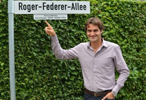 Swiss tennis player Roger Federer poses by a street sign reading his name near the Gerry Weber Stadium in the city of Halle western Germany on June 11, 2012 where the Halle ATP open started today. Fed ...