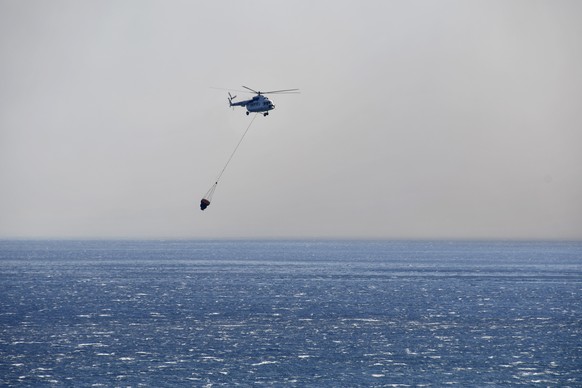 A helicopter takes part in a search and rescue operation near the eastern Aegean Sea island of Samos, Greece, Wednesday, July 13, 2022. A firefighting helicopter battling a blaze on the Greek island o ...