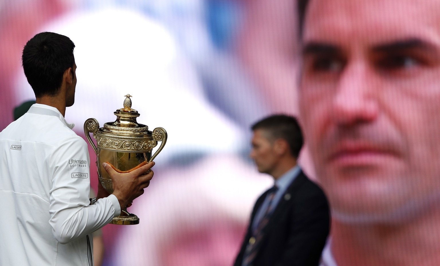 epa07717361 Novak Djokovic (L) of Serbia celebrates with the trophy after winning against Roger Federer of Switzerland during their Men&#039;s final match for the Wimbledon Championships at the All En ...