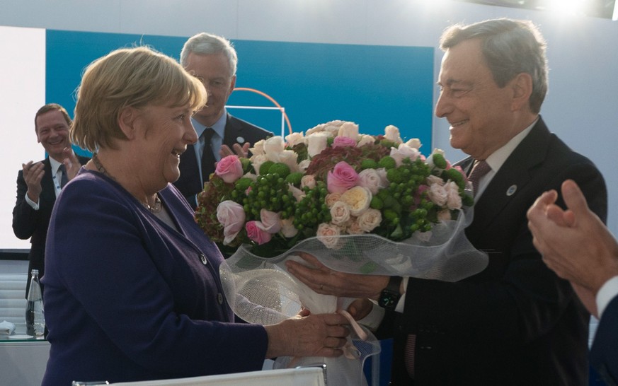 epa09556531 A handout photo made available by the Chigi Palace press office shows German Chancellor Angela Merkel (L) receiving a bouquet of flowers from Italian Prime Minister Mario Draghi at the end ...