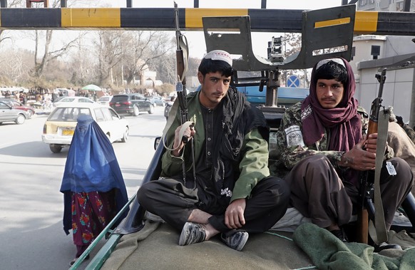 epa09640642 An Afghan burqa-clad woman walks as Taliban members guard a street in downtown Kabul, Afghanistan, 13 December 2021. Minister of virtue and vice, Sheikh Mohammad Khalid Hanafi stated on 13 ...