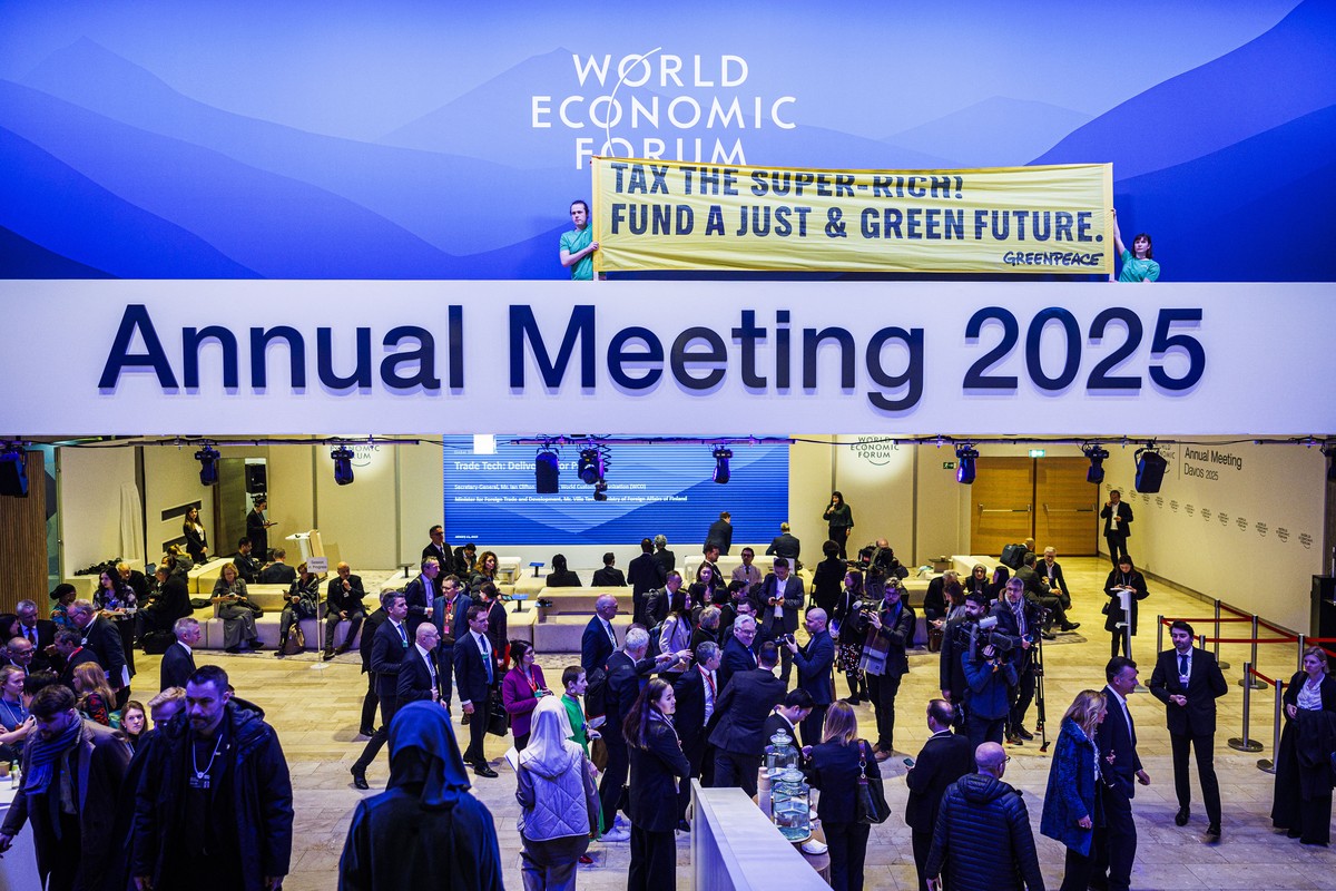 Greenpeace activists hold a banner in front of the congress hall as they stage an action during the 55th annual meeting of the World Economic Forum, WEF, in Davos, Switzerland, Tuesday, January 21, 20 ...