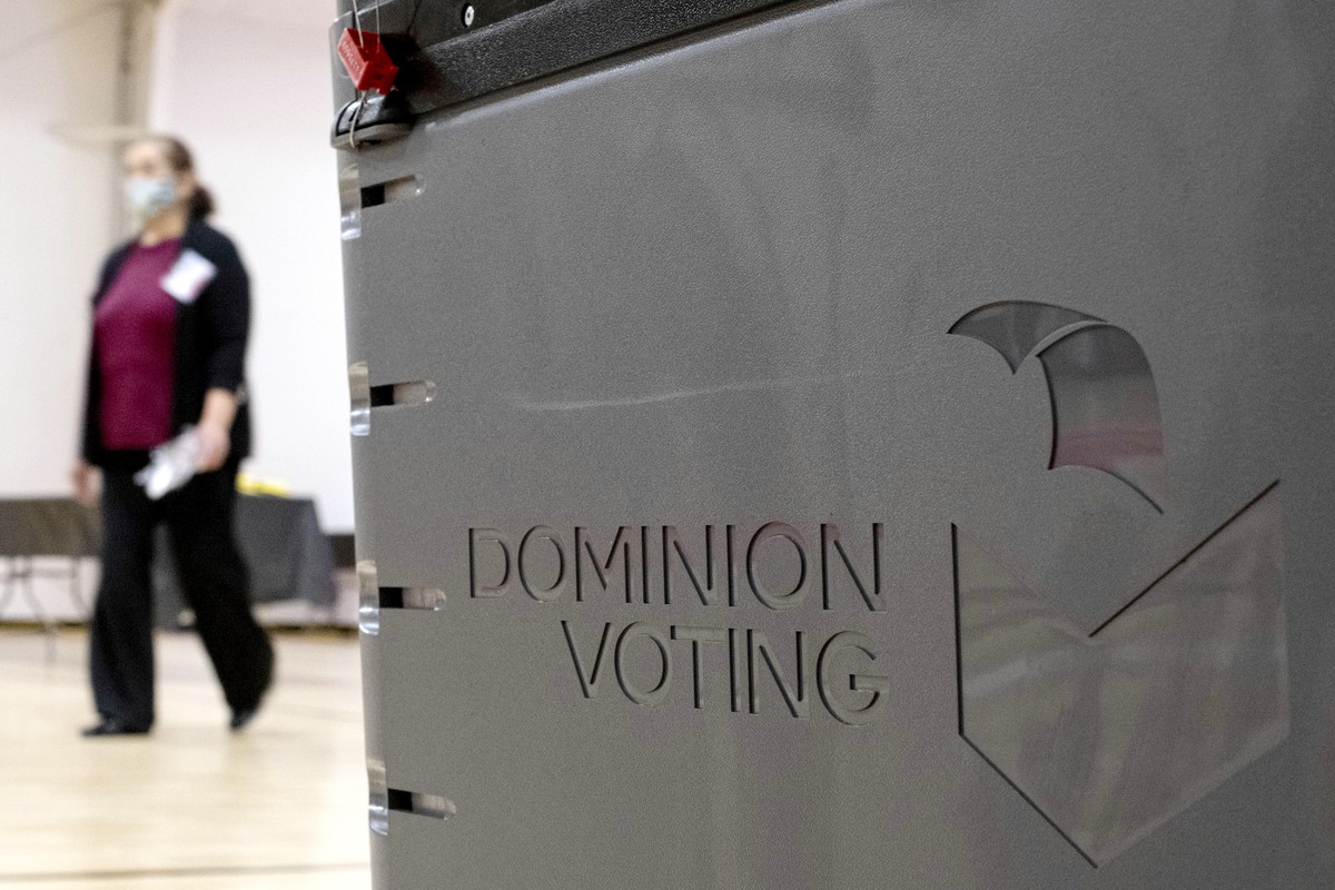 FILE - A worker passes a Dominion Voting ballot scanner while setting up a polling location at an elementary school in Gwinnett County, Ga., outside of Atlanta on Jan. 4, 2021. (AP Photo/Ben Gray, Fil ...