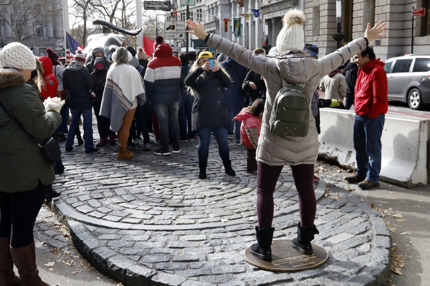 A woman poses for photos as she stands stands on a plaque marking the former location of the &quot;Fearless Girl&quot; statue, in New York&#039;s Financial District, Wednesday, Nov. 28, 2018. The stat ...
