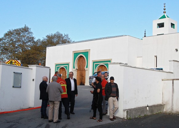 Local residents, firemen and police officers stand outside a mosque after an incident in Bayonne, southwestern France, Monday, Oct. 28, 2019. French authorities say a suspect has been arrested for all ...