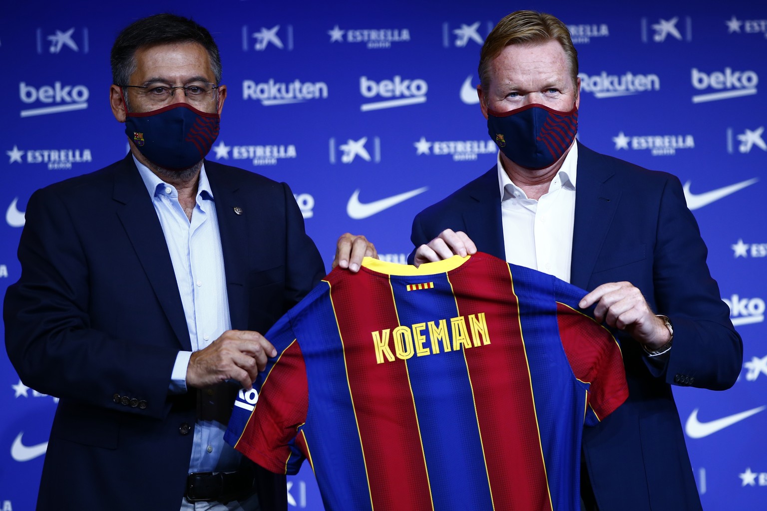 Ronald Koeman, right holds up a soccer shirt with his name on it while standing next to club Director Josep Bartome during his official presentation as coach for FC Barcelona in Barcelona, Spain, Wedn ...