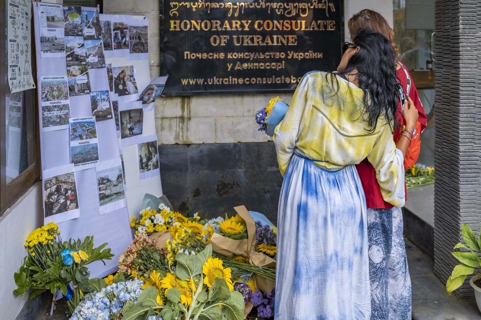 epa10487423 Ukrainian women lay flowers during a vigil in Denpasar, Bali February 24, 2023. Ukrainians in Bali celebrated the first anniversary of the Russian invasion of Ukraine with a vigil outside the ...