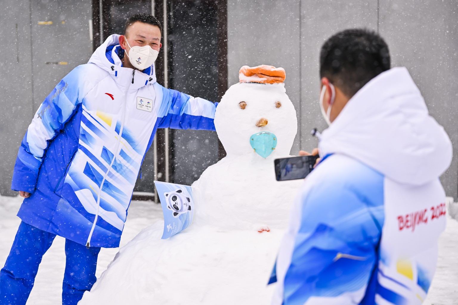 A volunteer poses next to a snowman for a picture before the second run of the men&#039;s Alpine Skiing giant slalom race at the 2022 Olympic Winter Games in Yanqing, China, on Sunday, February 13, 20 ...