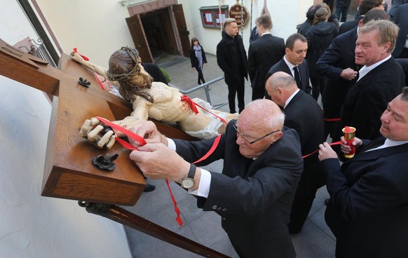 ARCHIV - 14.04.2017, Bayern, Lohr Am Main: Ein Mann trifft letzte Vorbereitungen an einem Kruzifix vor der Karfreitagsprozession durch die Innenstadt. (zu &quot;Von St