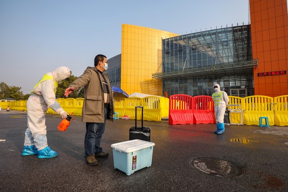 epa08236569 A worker disinfects a recovered COVID-19 patient discharged from a temporary hospital outside the Tazihu Gymnasium in Wuhan, Hubei province, China, 21 February 2020 (issued 22 February 202 ...