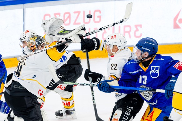 Torhueter Niklas Schlegel (HCL), links, und Santeri Alatalo (HCL), Mitte, gegen Mike Kuenzle (EVZ) im Spiel der Eishockey National League zwischen dem EV Zug, EVZ, und dem HC Lugano, HCL, am Freitag,  ...