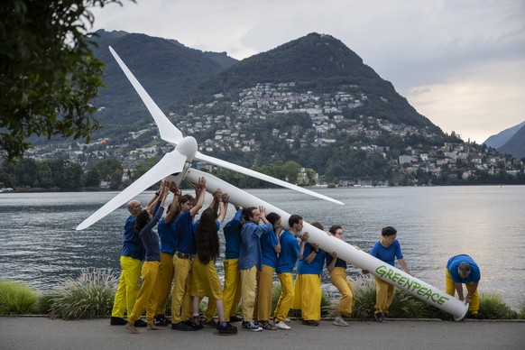 epa10051018 Activits of Greenpeace raise a replica wind turbine on the shore of Lake Lugano on the sidelines of the Ukraine Recovery Conference URC, in Lugano, Switzerland, 04 July 2022. Greenpeace ca ...