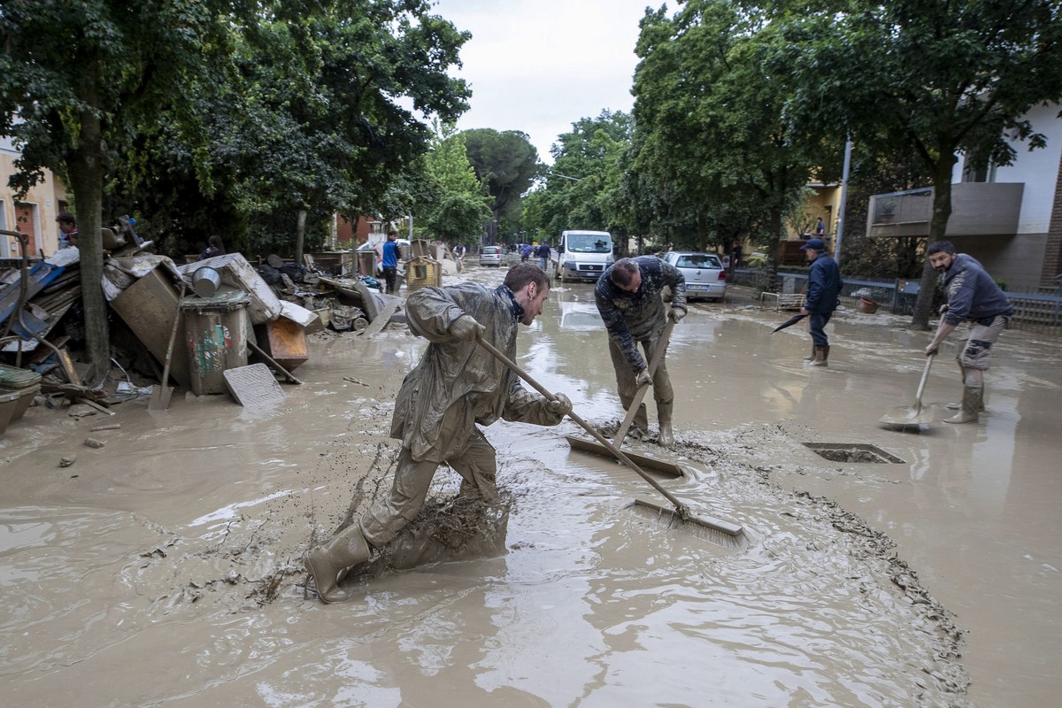 epa10639542 People work to clean a water-logged street following the flood that is affecting Emilia-Romagna region, in Faenza, Italy, 19 May 2023. Italy's northeastern region and parts of the Adr ...