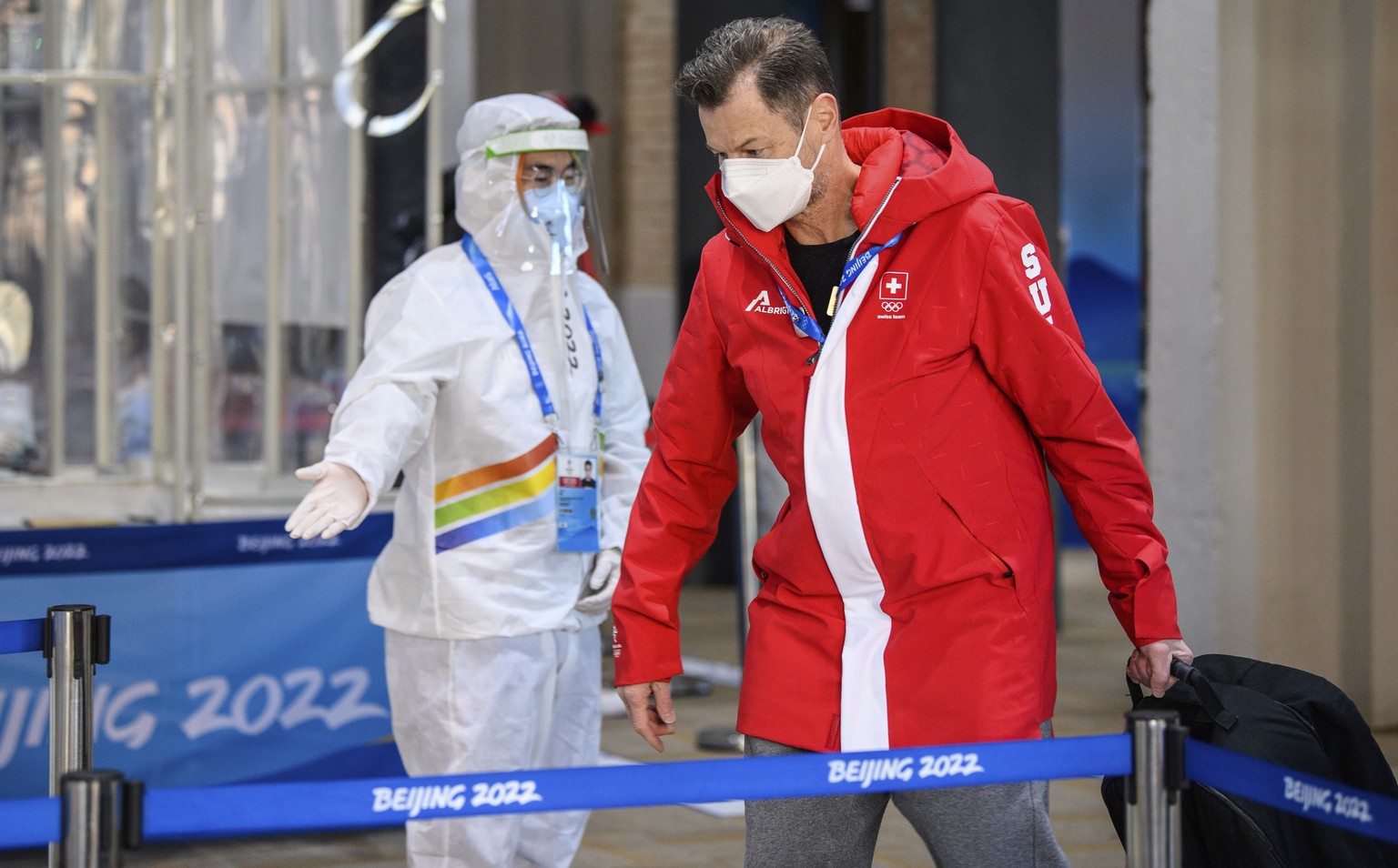 A member of Team Switzerland walks past security as he arrives at the Olympic Village ahead of the 2022 Winter Olympics, Tuesday, Feb. 1, 2022, in Beijing. (Anthony Wallace/Pool Photo via AP)