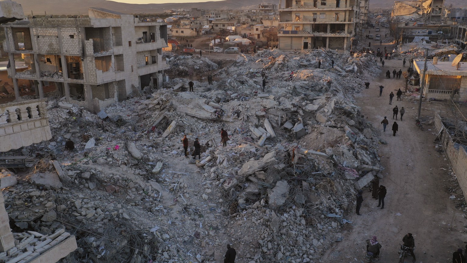 People walk past collapsed buildings after a devastating earthquake hit the town of Jinderis, Aleppo province, Syria, Thursday, February 9, 2023. The earthquake that flattened thousands of buildings was one of the…