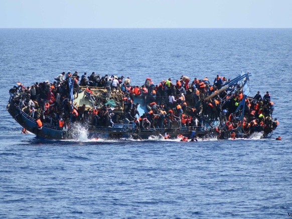FILE - In this May 25, 2016 file photo made available by the Italian Navy, people try to jump in the water right before their boat overturns off the Libyan coast. Over 700 migrants are feared dead in  ...
