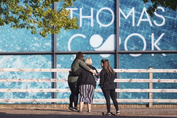 People gather outside the headquarters of tour operator Thomas Cook, in Peterborough, England, which has ceased trading with immediate effect after failing in a final bid to secure a rescue package fr ...