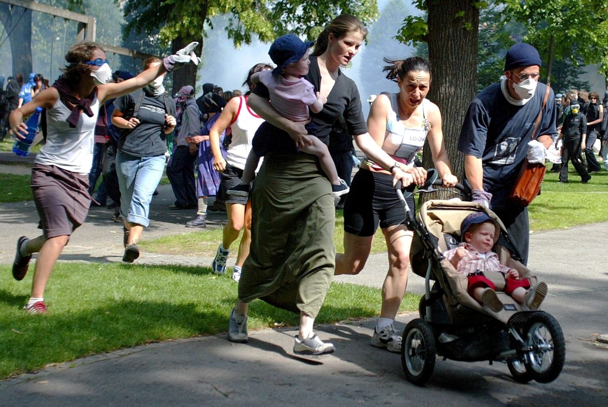 Anti-globalisation protestors, with maks, send away bystanders with young children as riot police officers spray tear gas during a anti G8 demonstration in Lausanne, Switzerland, Sunday, June 1st, 200 ...