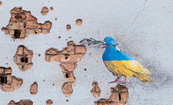 Shelled wall with a drawing of a dove in the colors of the flag of ukraine, blue and yellow. The dove is a symbol of purity, light, peace, love, the human soul. Ukraine, Kyiv - May 06, 2023 Model Rele ...