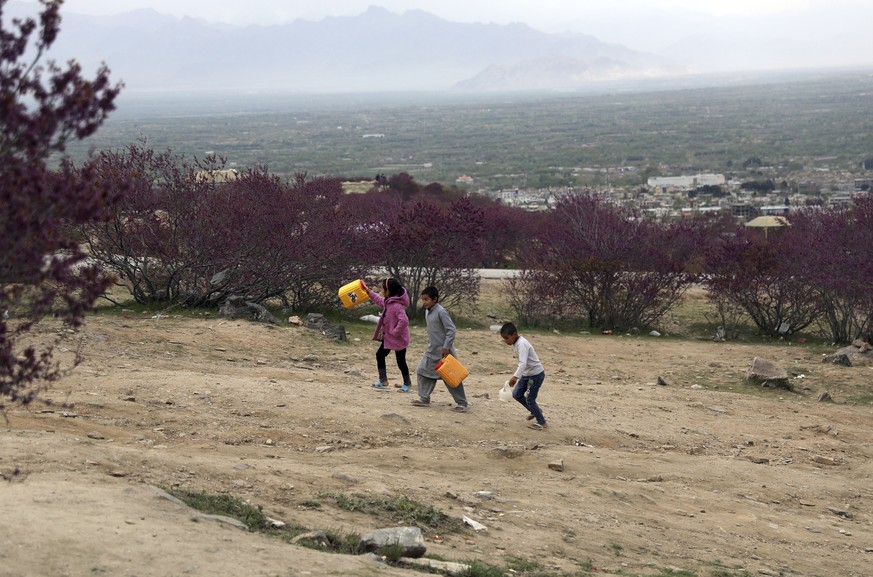 Afghan children carry containers of water, at Gul Ghundi park in the city of Charikar in Parwan province, north of Kabul, Afghanistan, Sunday, April 4, 2021. (AP Photo/Rahmat Gul)