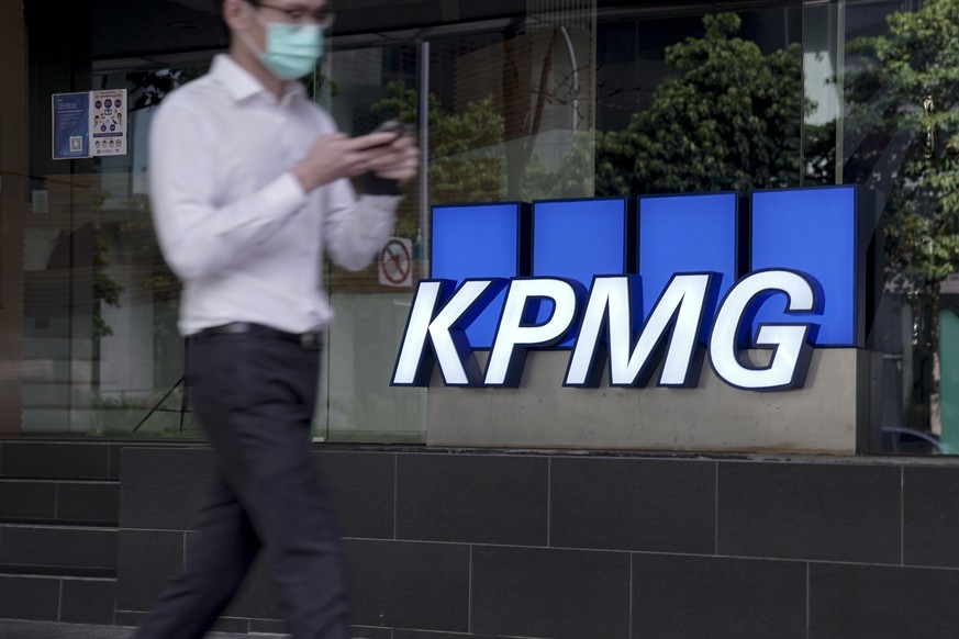 epa08777182 A man walks past the logo of auditing firm KPMG in the financial district in Singapore, 27 October 2020. The fallout of the global Covid-19 coronavirus pandemic has had a range of effects  ...