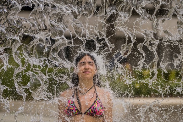 A woman cools off in a fountain in Cordoba, southern Spain, Sunday, July 11, 2021. Spain is suffering a weekend of record-breaking high temperatures, with the thermometer set to top 44 Celsius (111 Fa ...