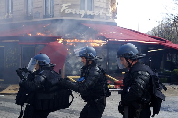 epa07442845 Riot police try to secure a perimeter in front of the Fouquet&#039;s restaurant on fire during the &#039;Act XVIII&#039; demonstration (the 18th consecutive national protest on a Saturday) ...