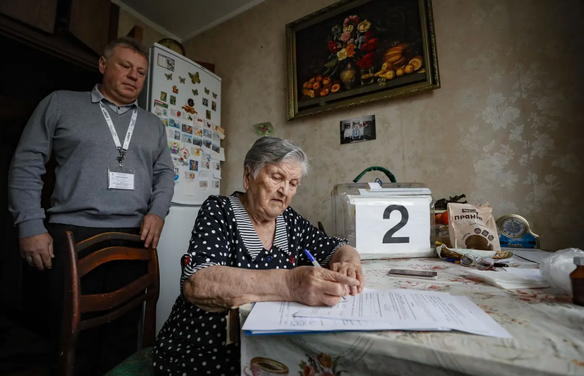 Un assistant surveille une retraitée dans son appartement à Moscou lors d'une tournée de vote mobile