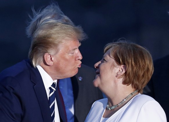 epaselect epa07793896 US President Donald J. Trump (L) kisses German Chancellor Angela Merkel (R) as they pose for the family photo during the G7 summit at Casino in Biarritz, France, 25 August 2019.  ...