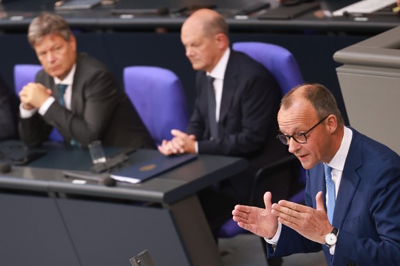 epa11392624 Chairman of the Christian Democratic Union (CDU) party and faction Friedrich Merz (R) speaks beside German Minister for Economy and Climate Action Robert Habeck (L) and German Chancellor O ...