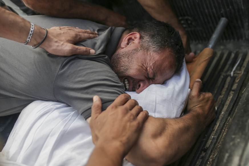 Palestinians mourn over the bodies of relatives killed in an Israeli airstrike, at a morgue in Al-Aqsa Martyrs Hospital in Deir al Balah, the Gaza Strip, Monday, June 10, 2024. (AP Photo/Jehad Alshraf ...